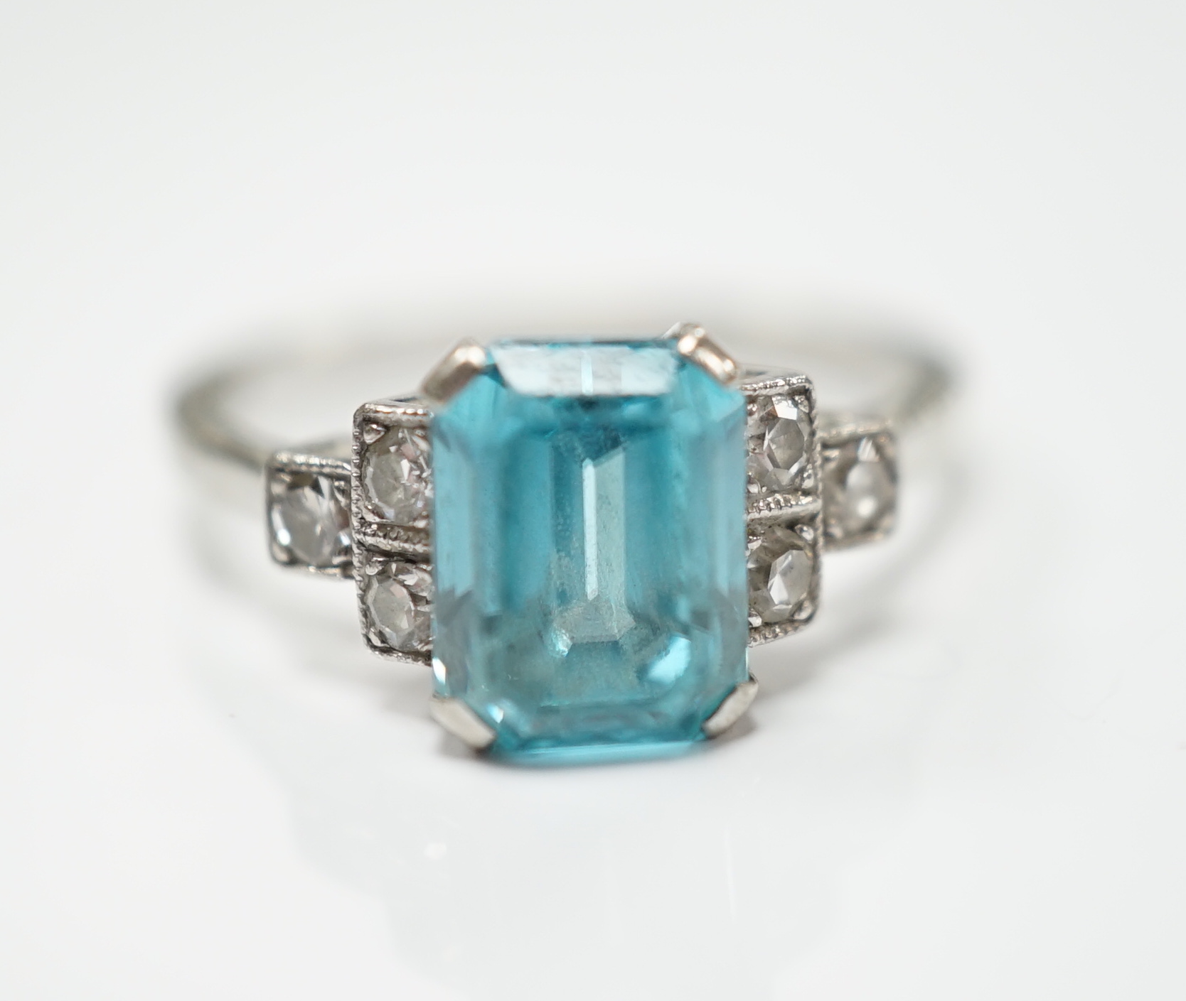 An 18ct, plat and single stone emerald cut blue zircon set ring, with six stone diamond set shoulders, size L, gross weight 2.9 grams.